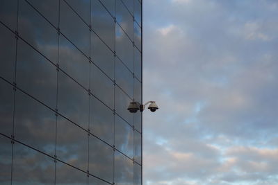 Security camera on building against cloudy sky