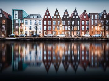 Houses by river in city against sky