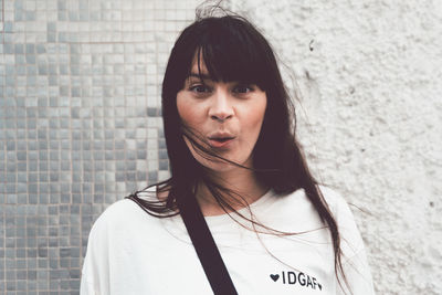 Portrait of young woman standing against wall