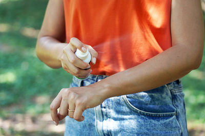 Girl spraying insect repellent on her arm outdoor in nature using spray bottle. mosquito repellent.