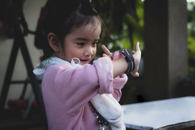 Close-up of cute girl checking time while standing in yard