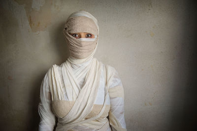 Portrait of woman wrapped with bandages against wall during halloween