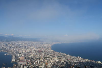 Aerial view of city buildings by sea against sky