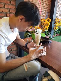 Midsection of man holding flower while sitting on table