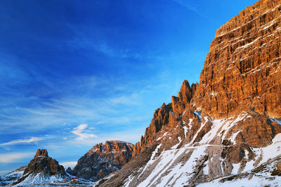 Low angle view of rocky mountain against blue sky