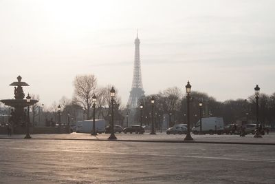 Vehicles on street with eiffel tower against sky during sunset