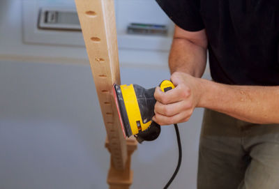 Midsection of carpenter using machinery on wood