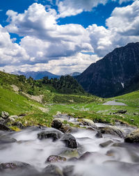 Scenic view of stream amidst mountains against sky