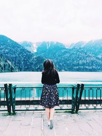 Rear view of woman standing on railing against mountain