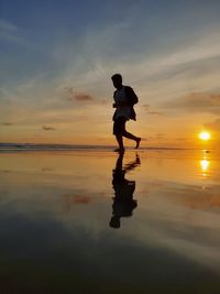 Full length of man on beach against sky during sunset