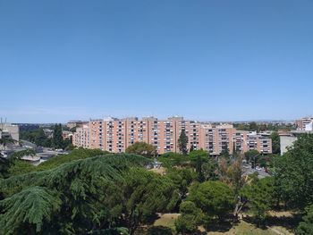 High angle view of trees and buildings against clear blue sky