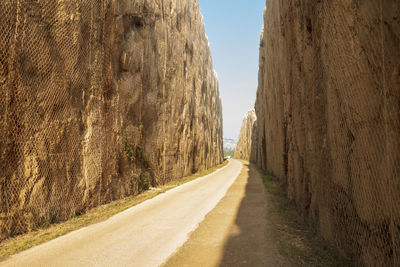 Road leading towards mountains against clear sky