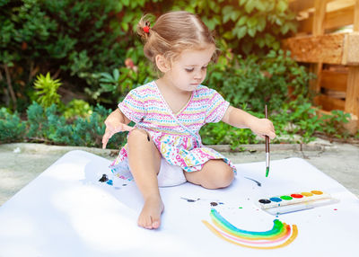 Full length of girl painting in paper against trees