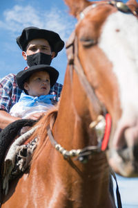 Argentinian father riding horse with his little boy