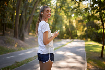 Side view of young woman using smart phone outdoors
