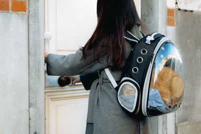 Portrait of a girl with a ginger pedigree cat in a backpack.