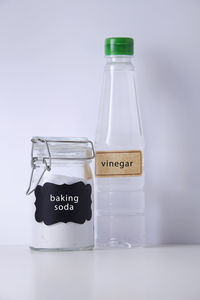 Close-up of baking soda and vinegar on table against white background