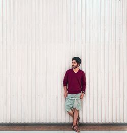 Full length of young man standing against wall