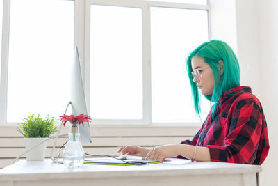 Young woman using mobile phone while sitting on table