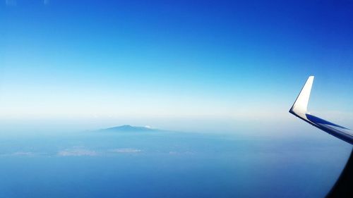 Airplane flying over landscape against clear blue sky