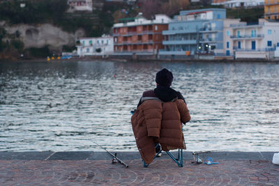 Rear view of man sitting on seat in city