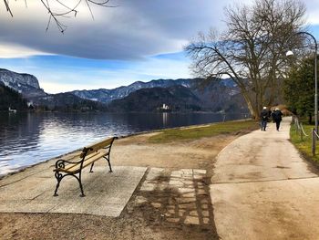 People by lake against sky