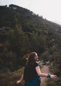 Side view of young woman against trees on mountain