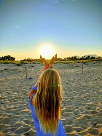 Optical illusion of woman holding sun at beach