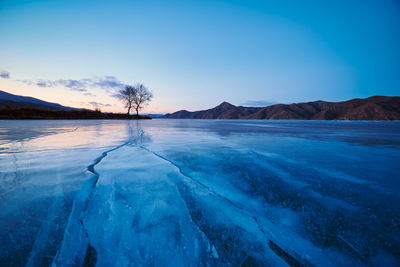 Scenic view of frozen lake against blue sky during sunset