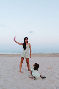 Mother making a selfie with her daughter on the beach by day