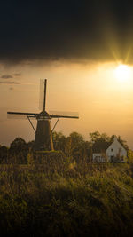 Traditional windmill on field against sky during sunset