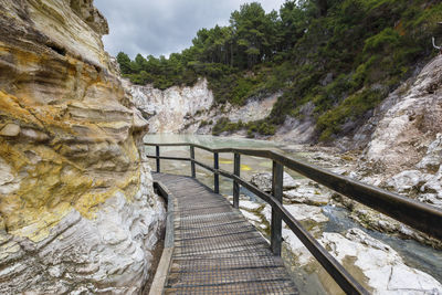 Footbridge amidst rocks against trees and mountains