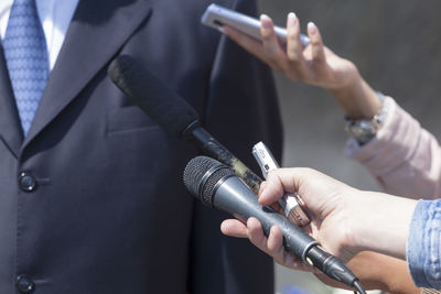 Cropped hand interviewing businessman with microphone