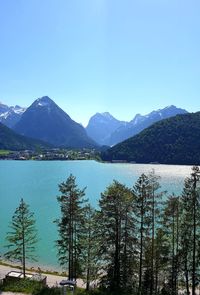 Scenic view of lake and mountains against clear blue sky