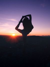 Silhouette woman standing on landscape against sunset sky