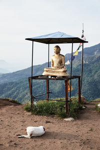 Man sitting on column against sky