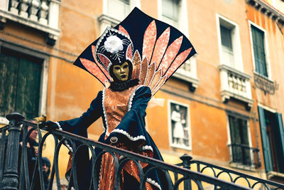 Low angle view of woman standing in mask against building