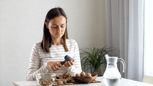 Young woman sitting by table at home