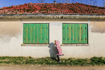 Girl standing by house