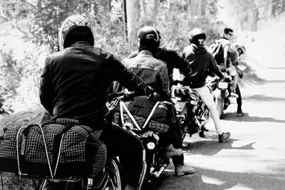 Rear view of people riding motorcycle on road