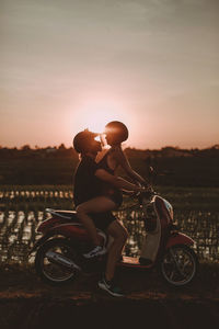 Couple kissing against sky during sunset