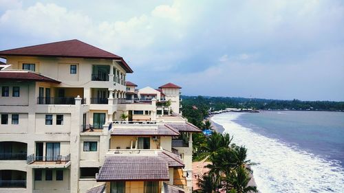 Buildings by sea against sky