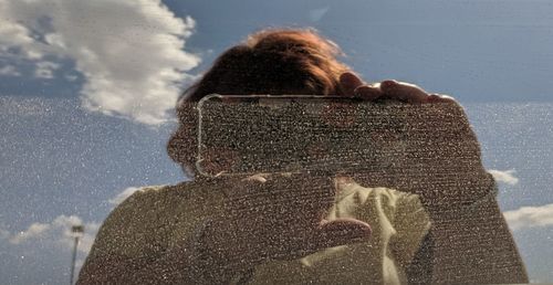 Rear view of woman photographing against sky