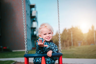 Portrait of happy boy sitting on slide at playground