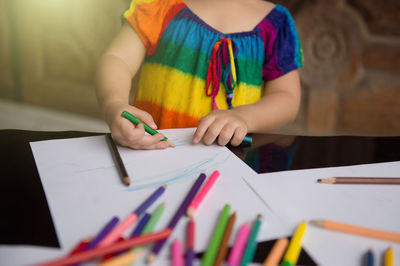 Midsection of girl drawing on paper at table