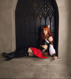 Portrait of fashion model wearing costume sitting on window sill