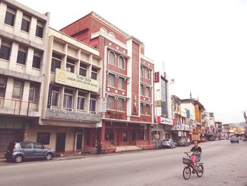 Cars on street in city against sky