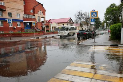 Wet street by buildings in city during rainy season