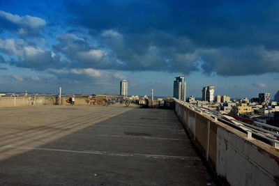 Road by buildings against sky in city