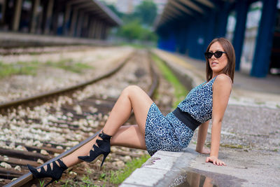 Young woman wearing sunglasses on railroad track